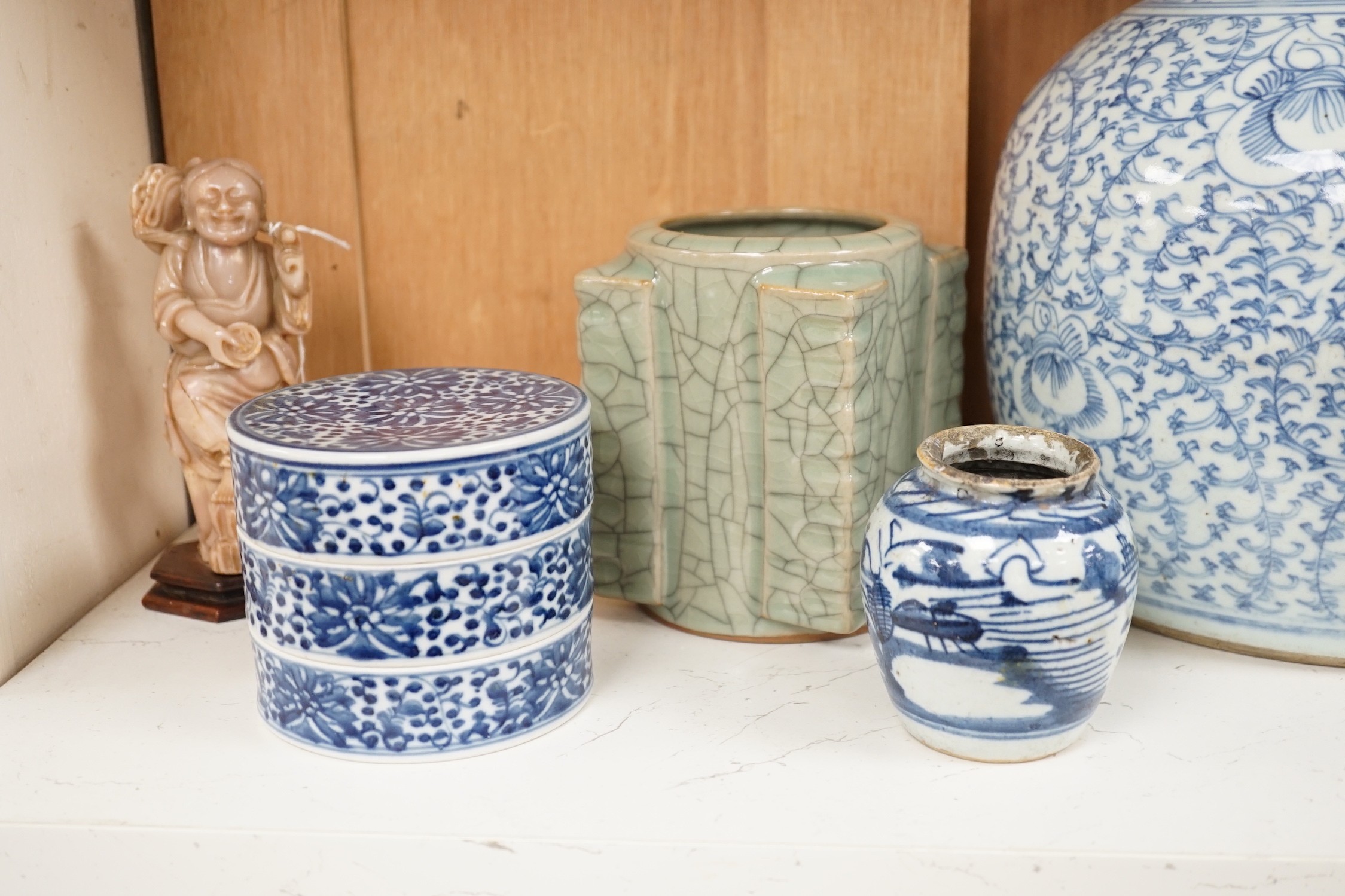 A group of 19th century blue and white jars, a stacking food box and two bowls, together with a celadon glazed cong vase and a soapstone figure of Liu Hai. Tallest 24cm
